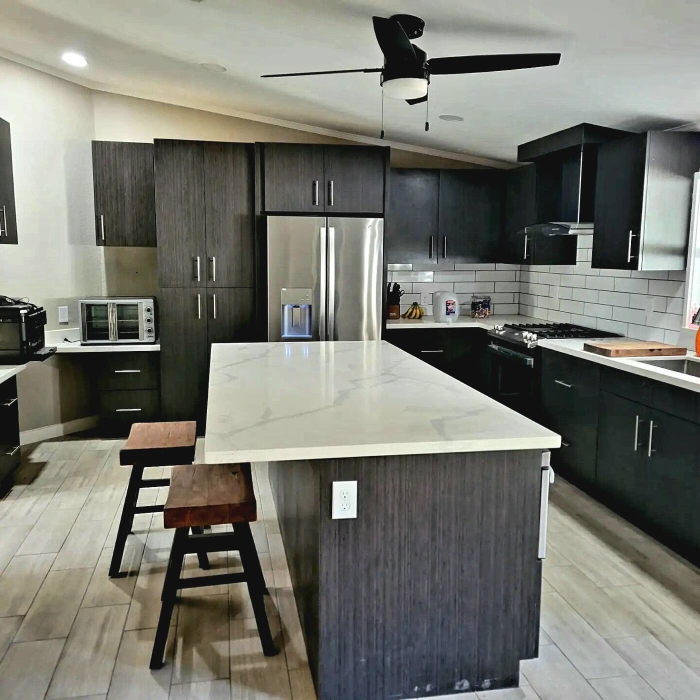 Kitchen island with white quartz top, stools and open ceiling fan