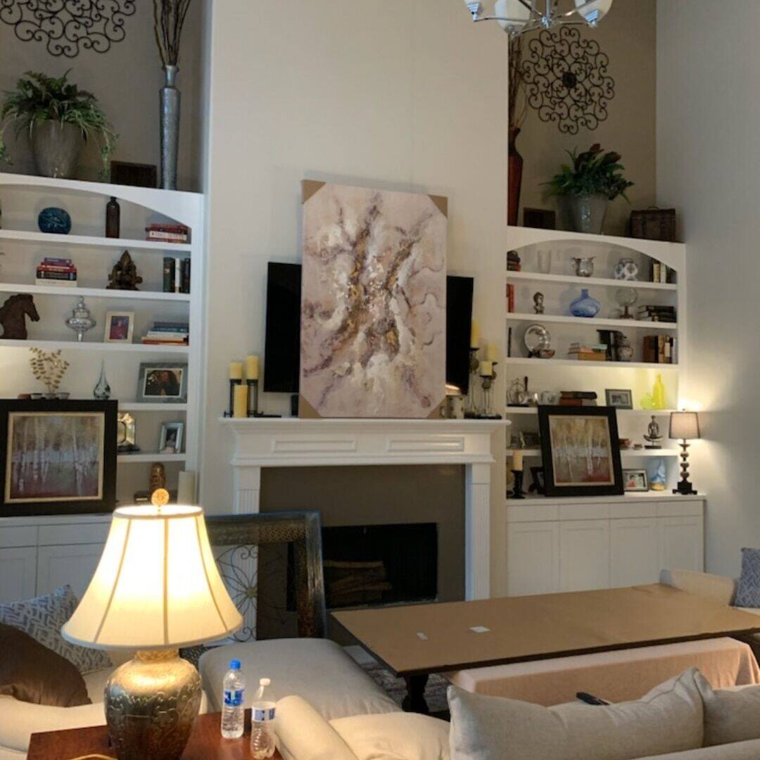 White built-in bookshelves flanking fireplace with art niches
